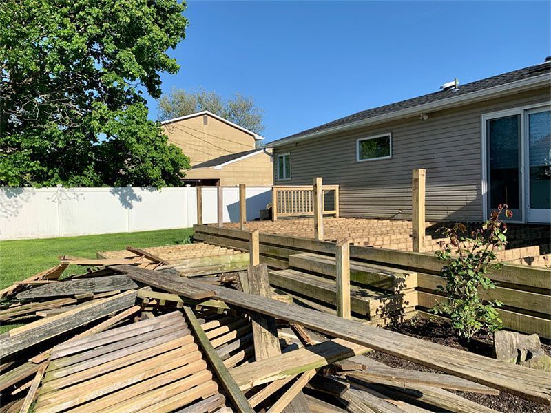 A pile of wood is sitting in front of a house.