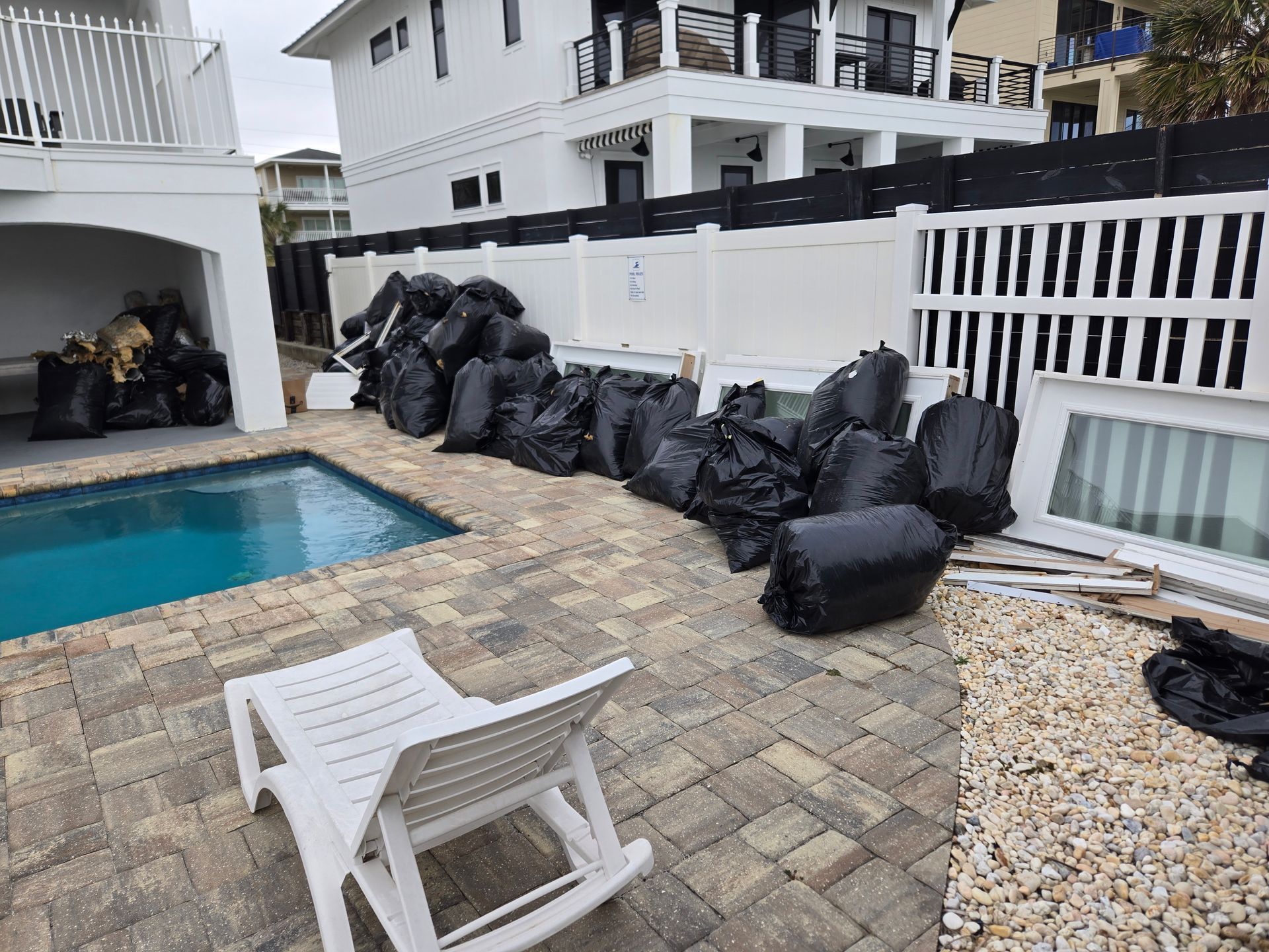 A pile of trash bags is sitting next to a swimming pool.