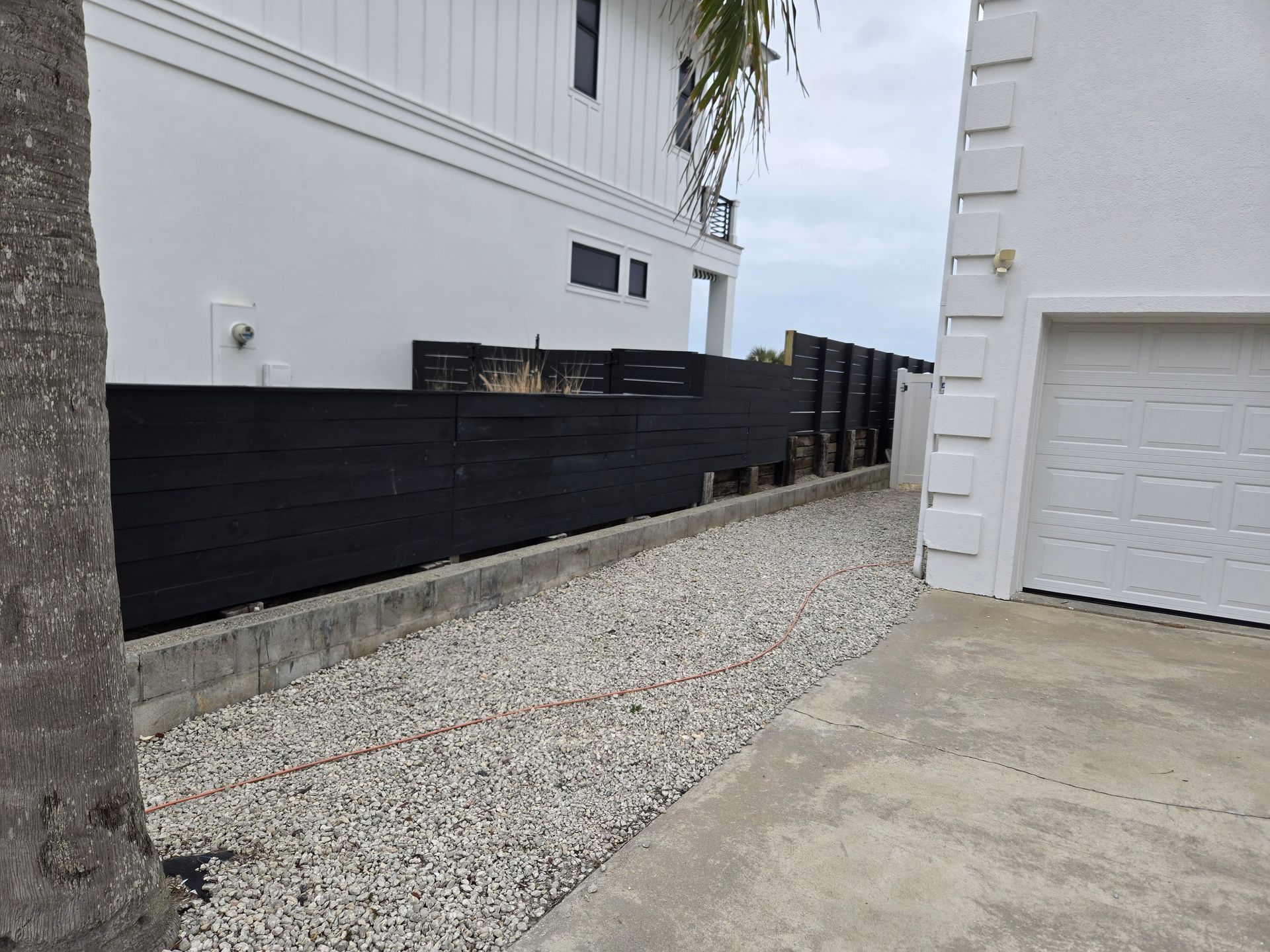 A white house with a black fence and a white garage door