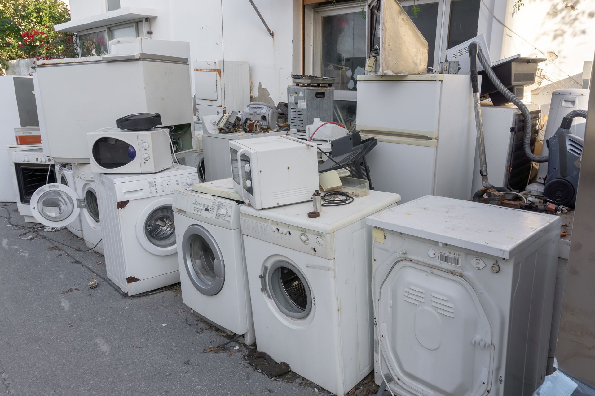 A bunch of old appliances are stacked on top of each other on the side of the road.