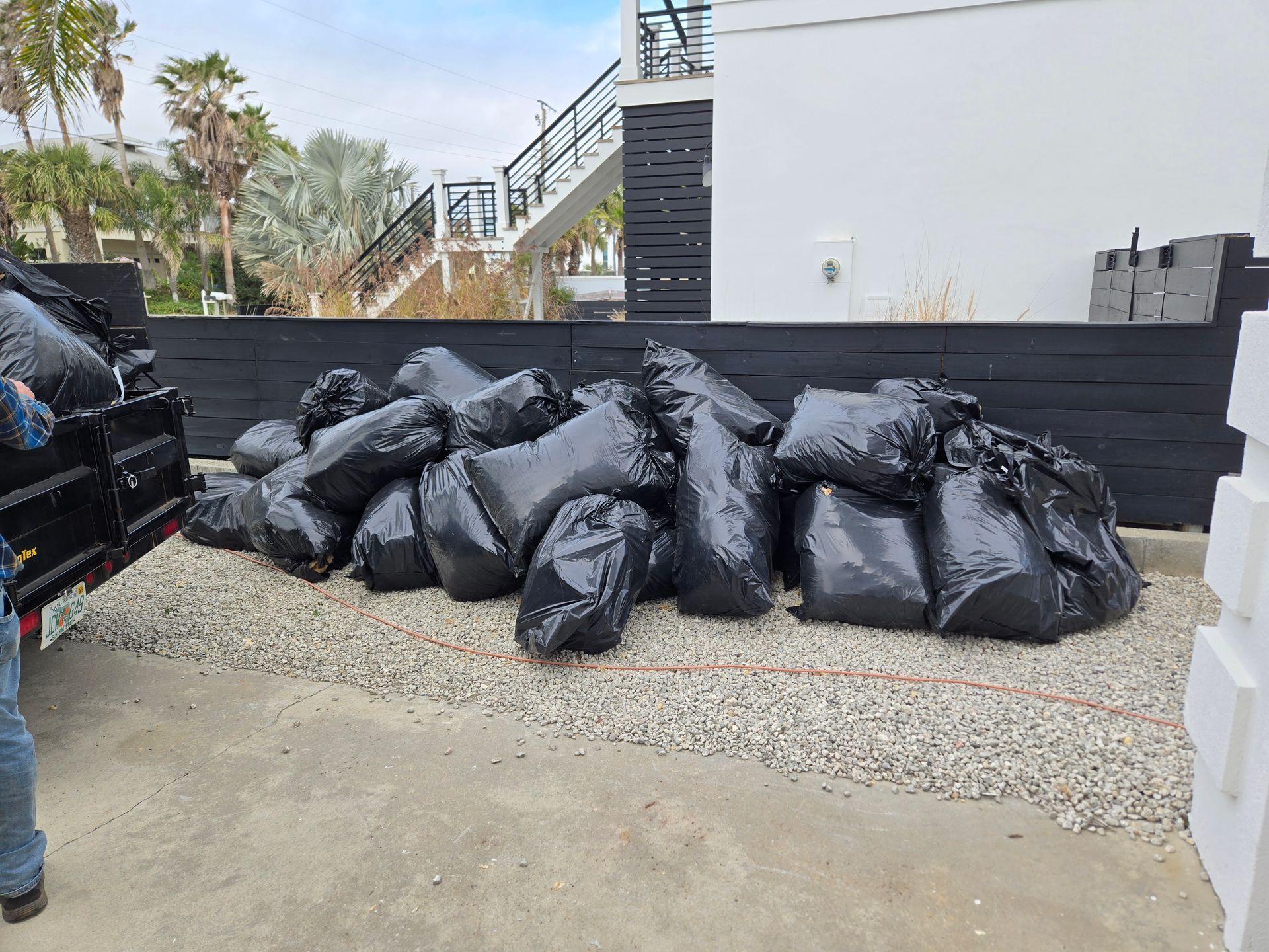 A pile of trash bags is sitting on the ground in front of a building.