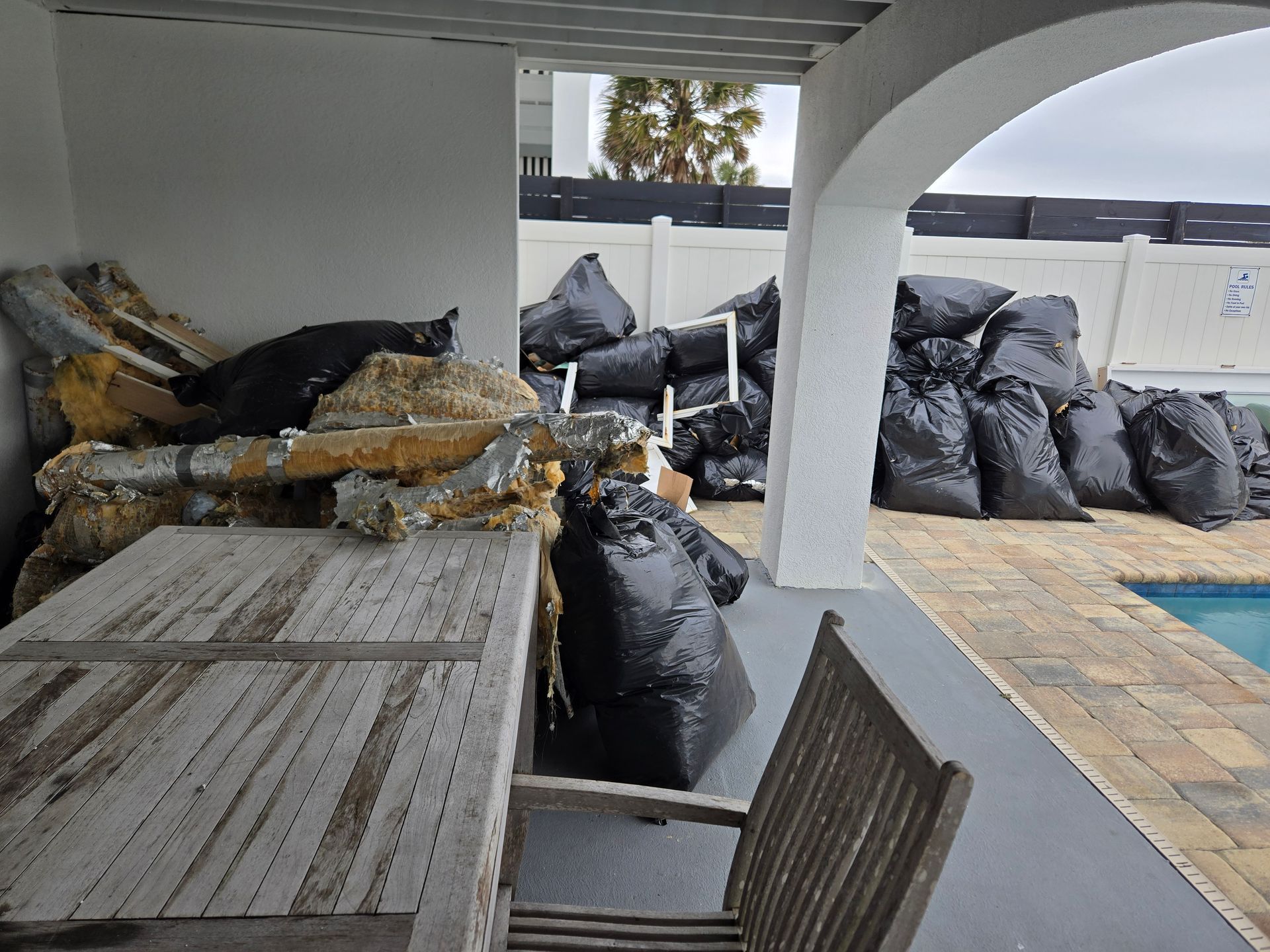 A patio with a table and chairs and a pile of trash bags