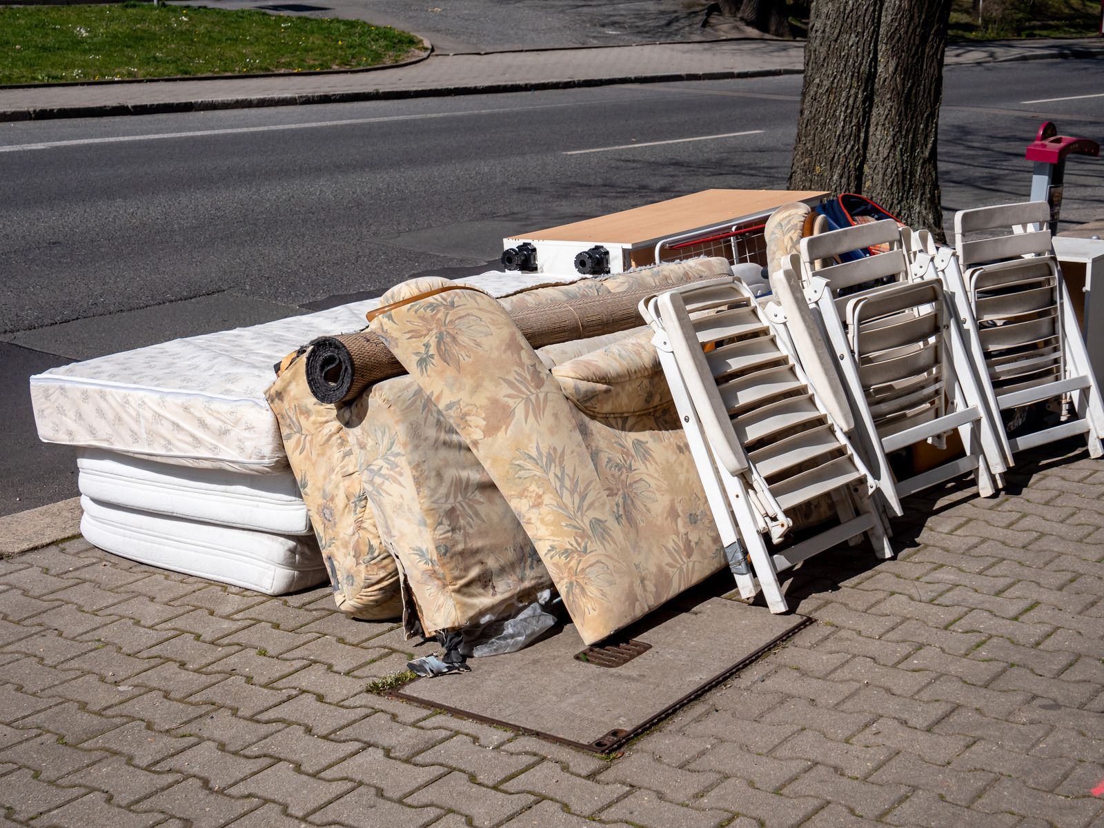 A pile of furniture is sitting on the side of the road.