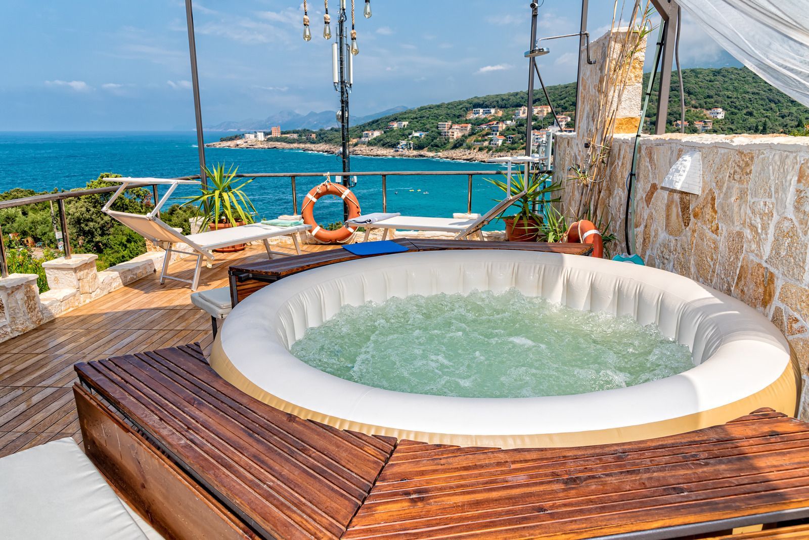 A hot tub is sitting on a wooden deck overlooking the ocean.