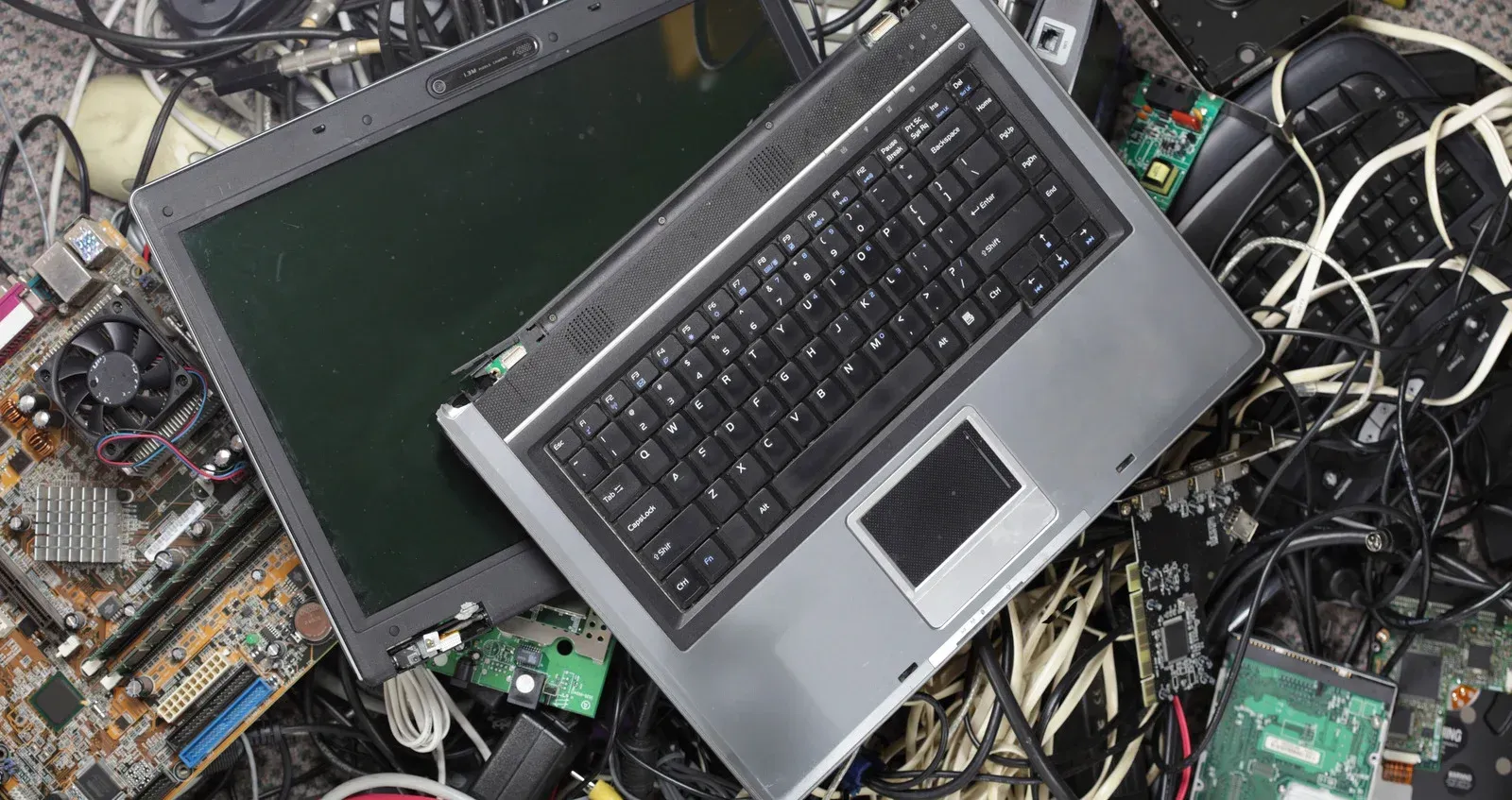 A laptop computer is sitting on top of a pile of computer parts.