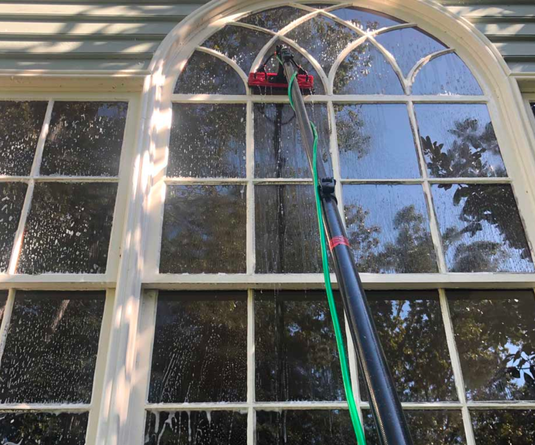 A person is cleaning a window with a hose.