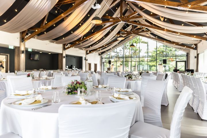 A large room with tables and chairs set up for a wedding reception.