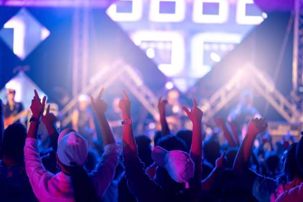 A crowd of people are raising their hands in the air at a concert.