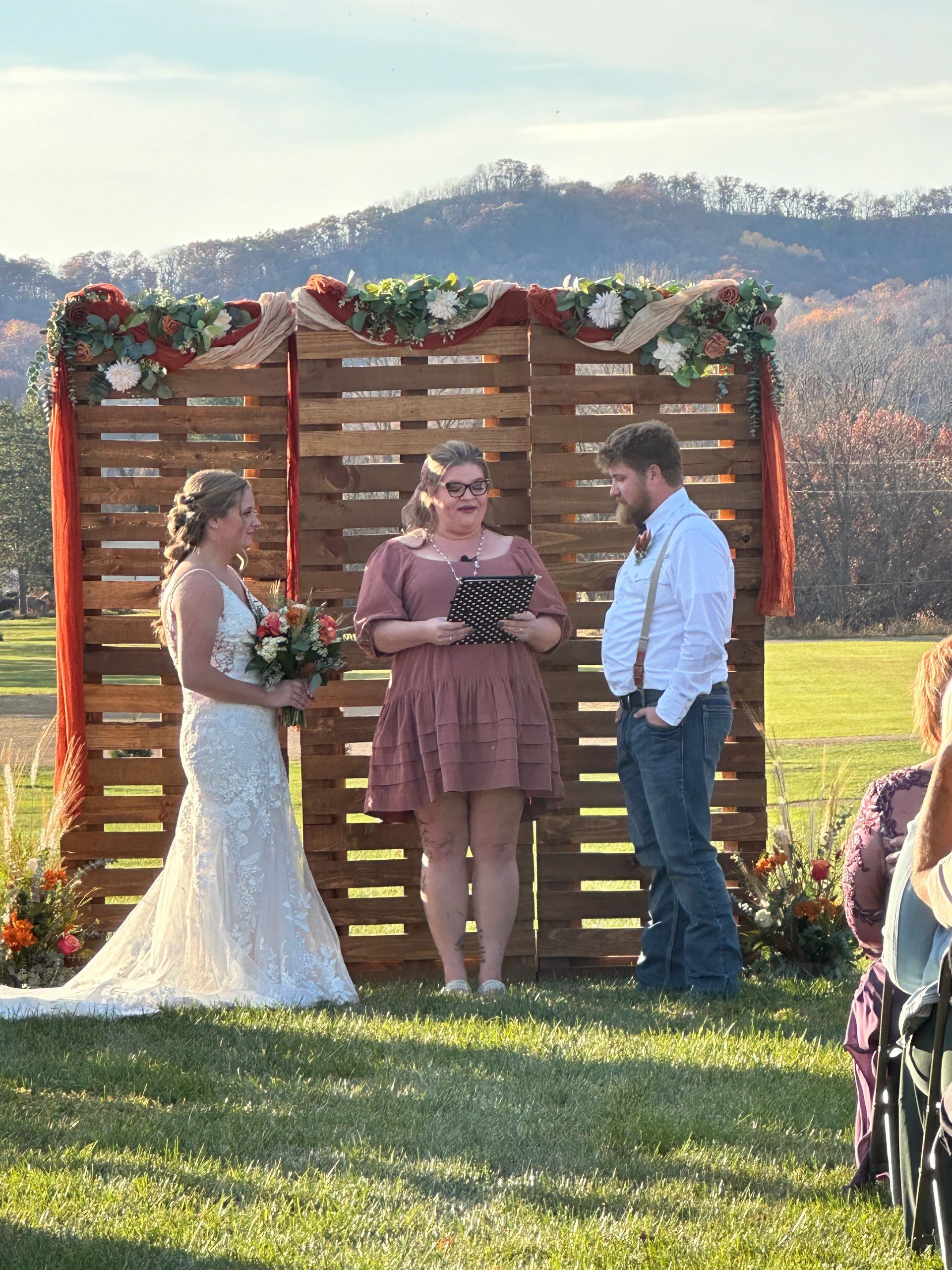 A bride and groom are standing in front of a wooden wall during their wedding ceremony.