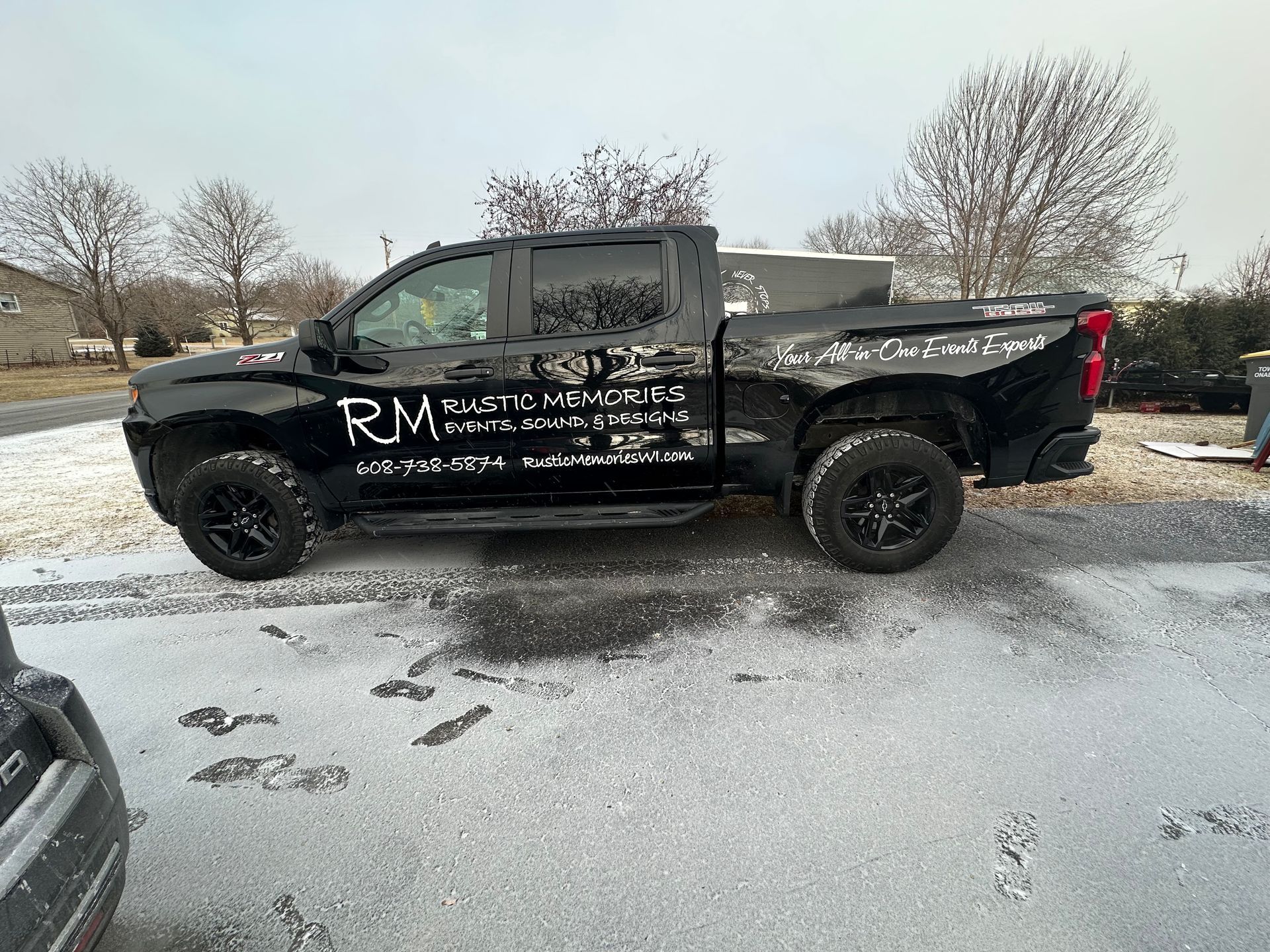 A black truck is parked in the snow in a parking lot.