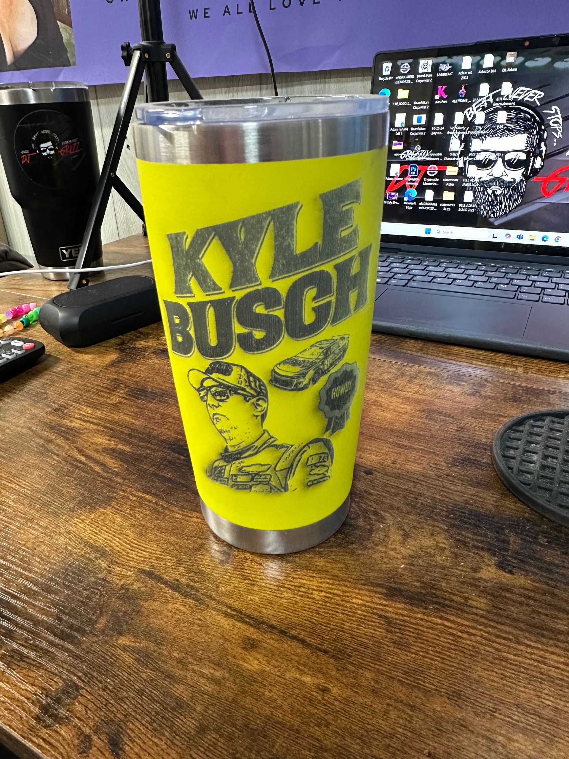 A yellow kyle busch tumbler is sitting on a wooden table.