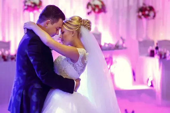 A bride and groom are dancing their first dance at their wedding reception.