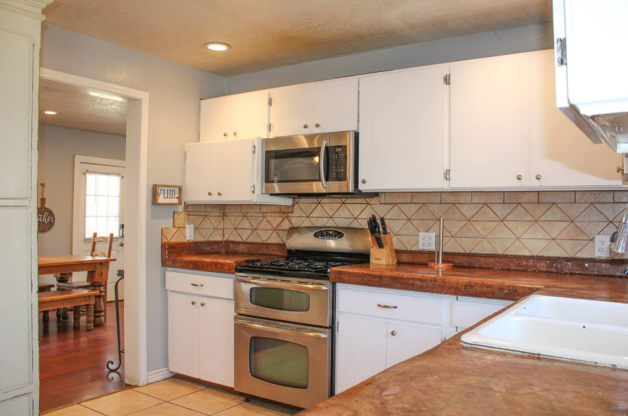 A kitchen with white cabinets and stainless steel appliances