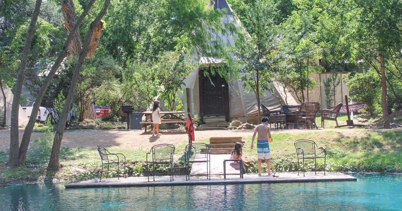A group of people standing on a dock next to a body of water.