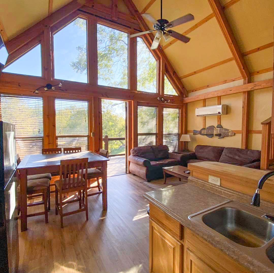 A living room with a ceiling fan and a table and chairs