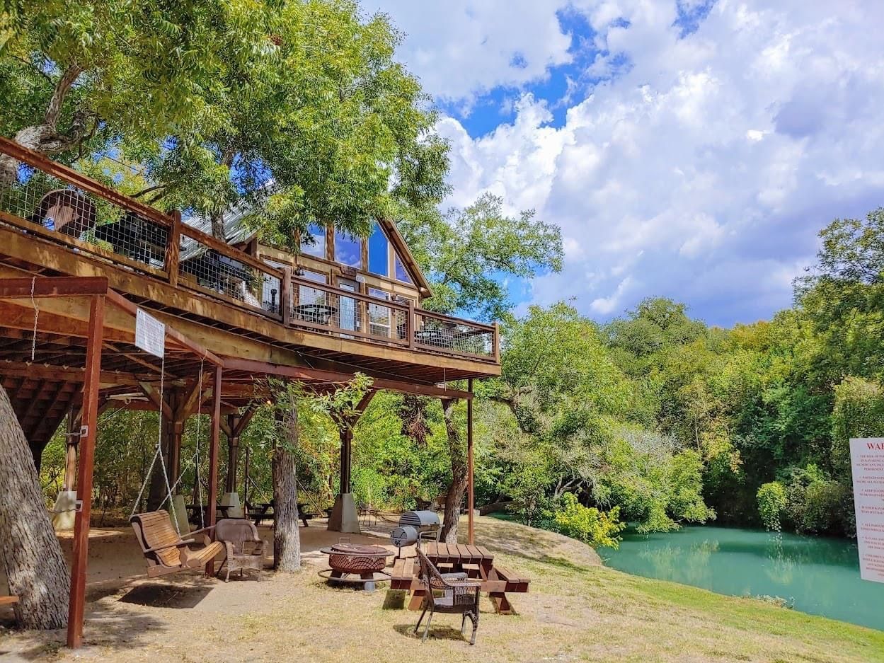 A wooden bridge over a river with a picnic table in the foreground.