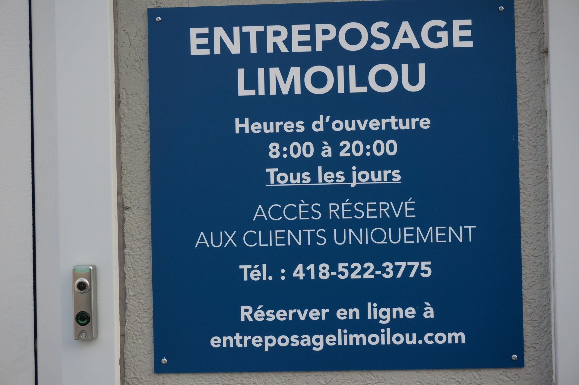 Panneau bleu de l'Entrepôt Limoilou avec horaires, numéro de téléphone et site web. Texte blanc.