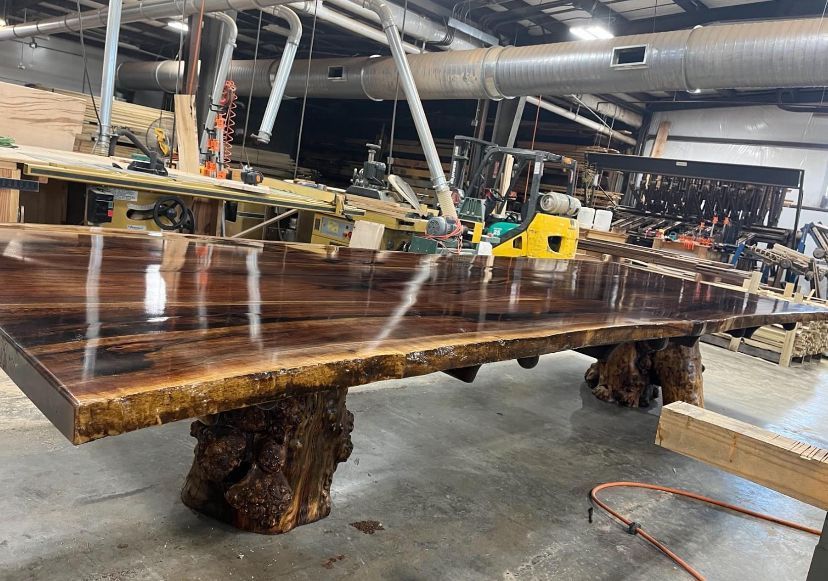 A large wooden table is sitting in a warehouse.