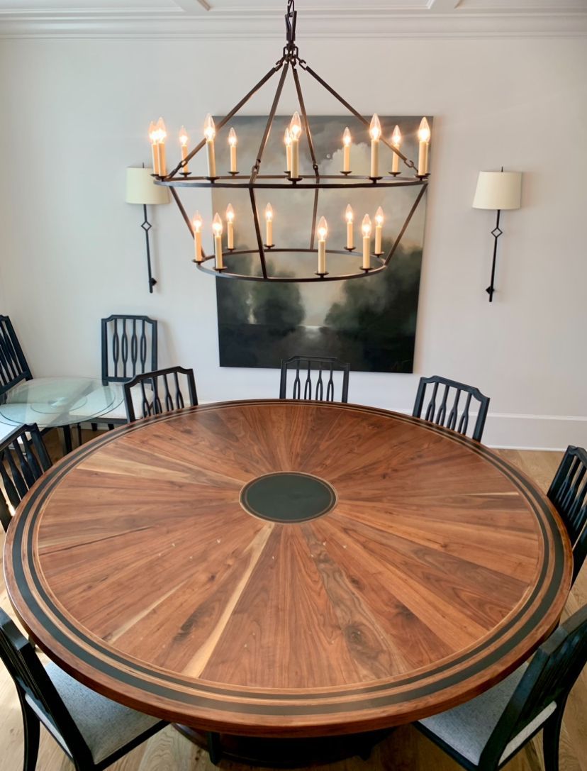 A dining room with a round table and chairs and a chandelier
