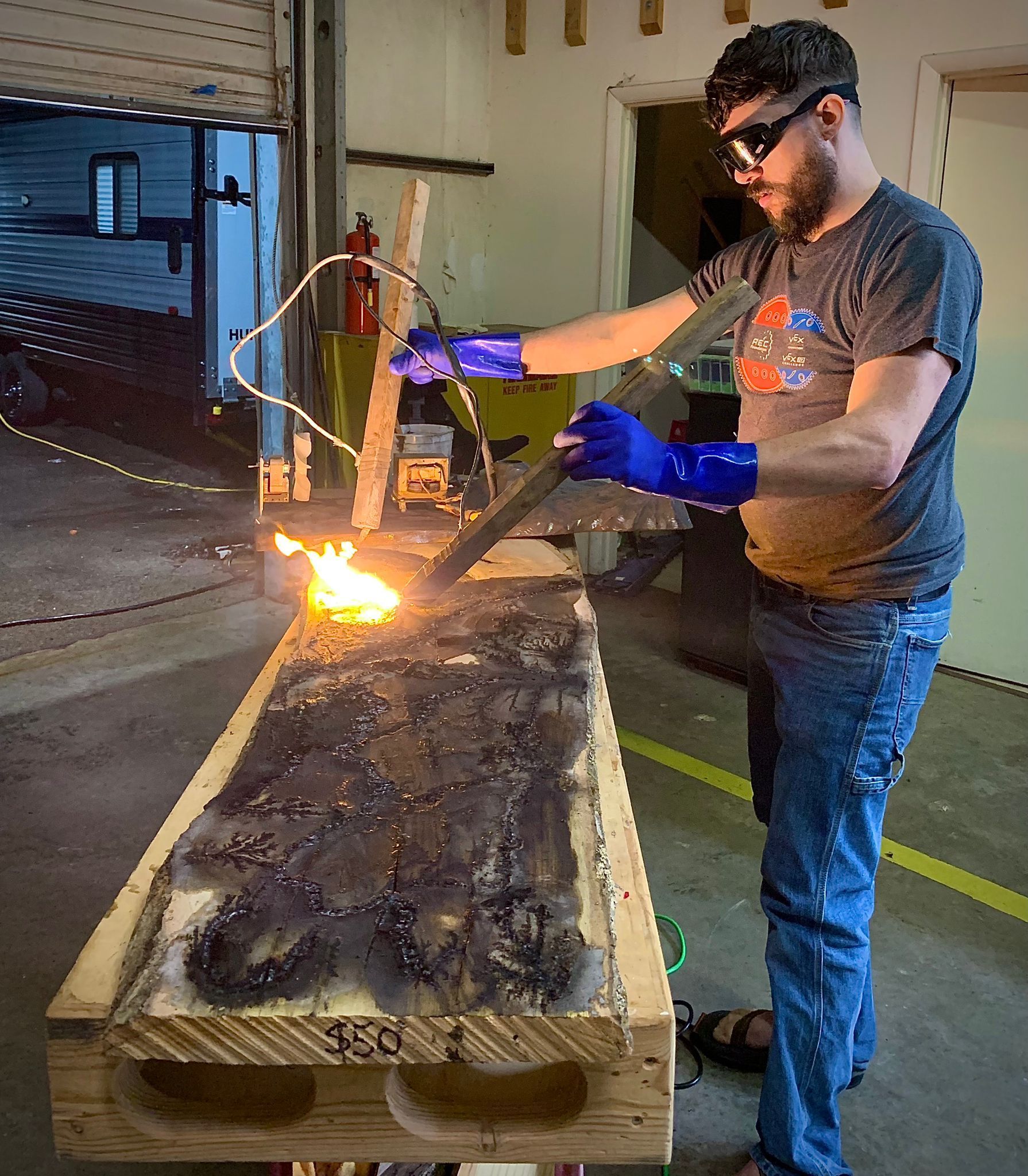 A man is cutting a piece of wood with a torch.