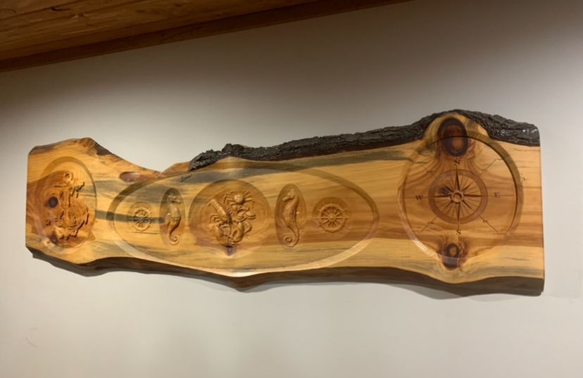 A wooden sculpture is hanging on a white wall.