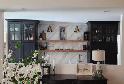 A living room with black cabinets , shelves , a desk and a lamp.