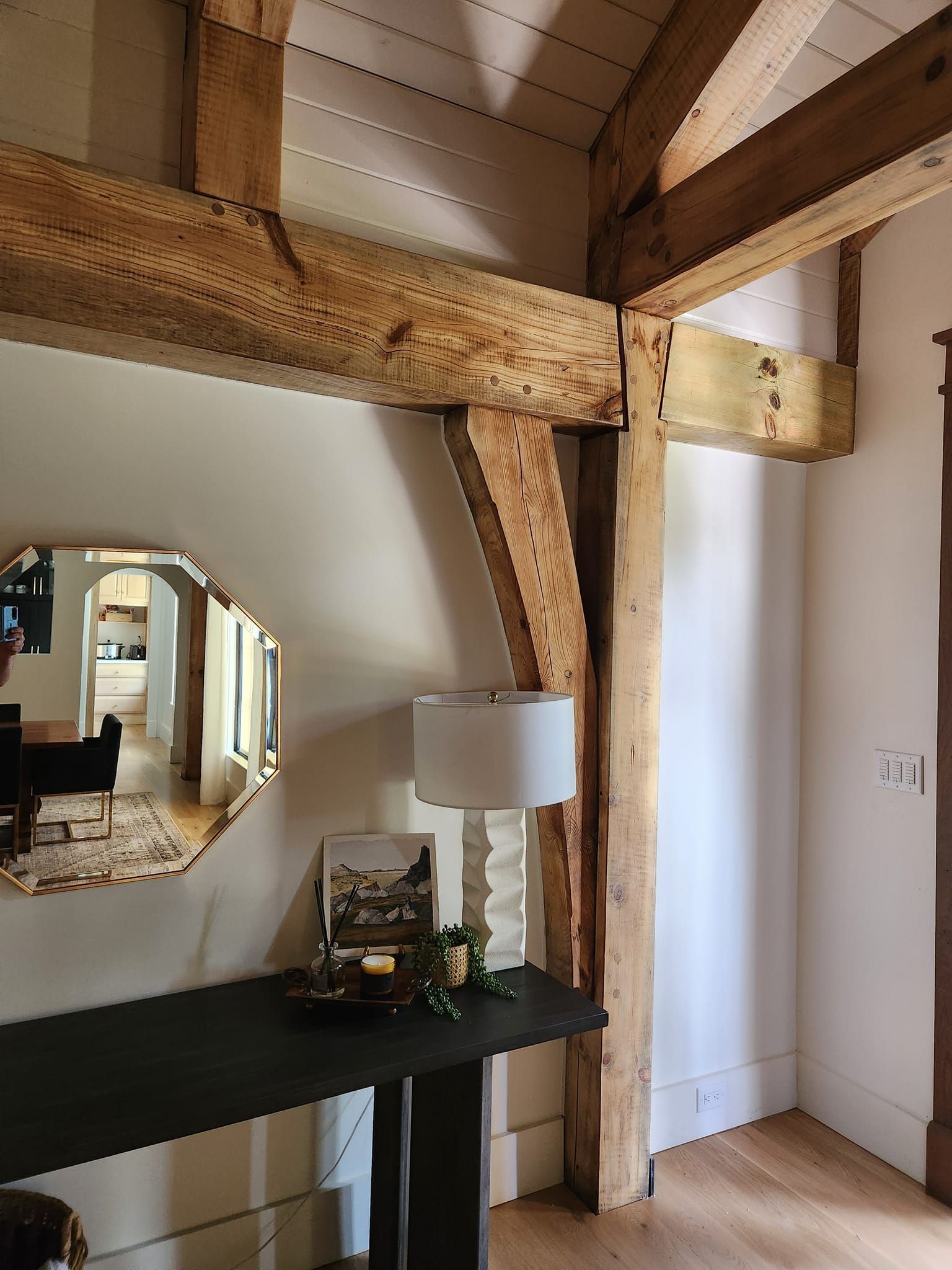 A room with wooden beams and a table with a lamp on it
