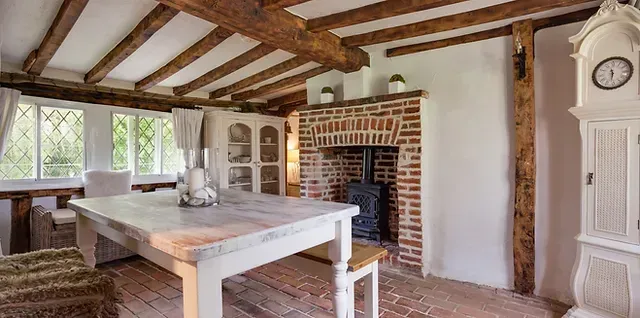 A living room with a table , chairs , clock and fireplace.