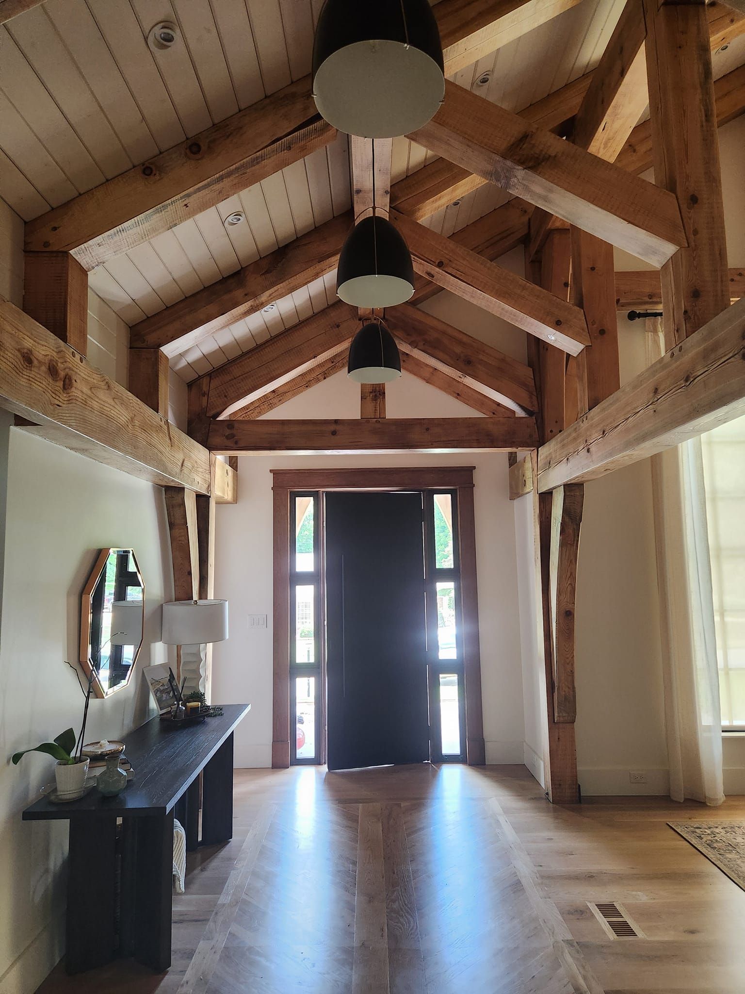 A large hallway with wooden beams and a black door.