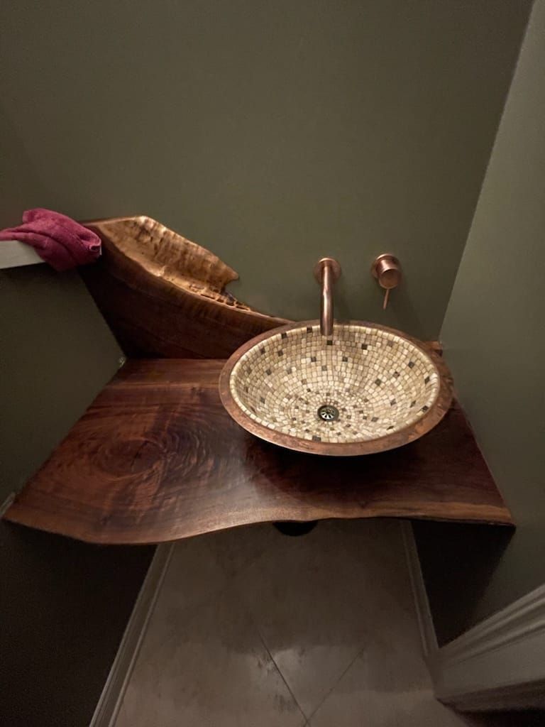 A wooden sink is sitting on a wooden counter in a bathroom.
