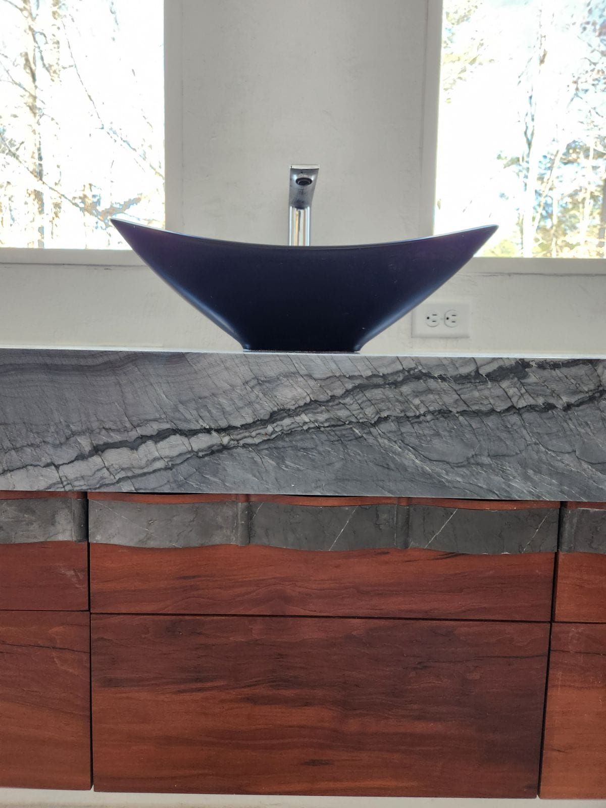 A bathroom sink is sitting on top of a wooden counter.
