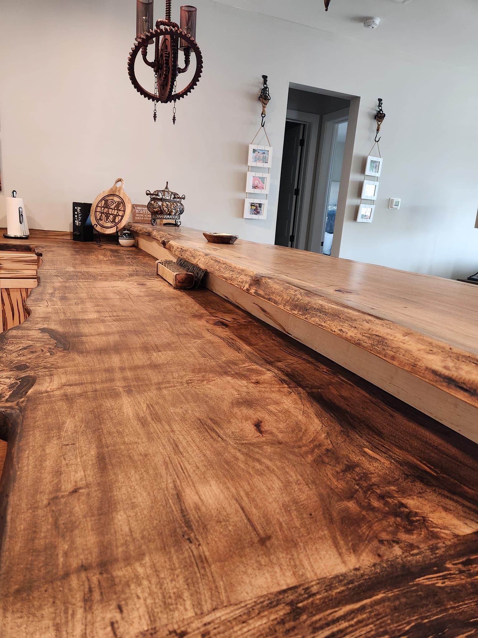 A long wooden table in a living room with a chandelier hanging from the ceiling.
