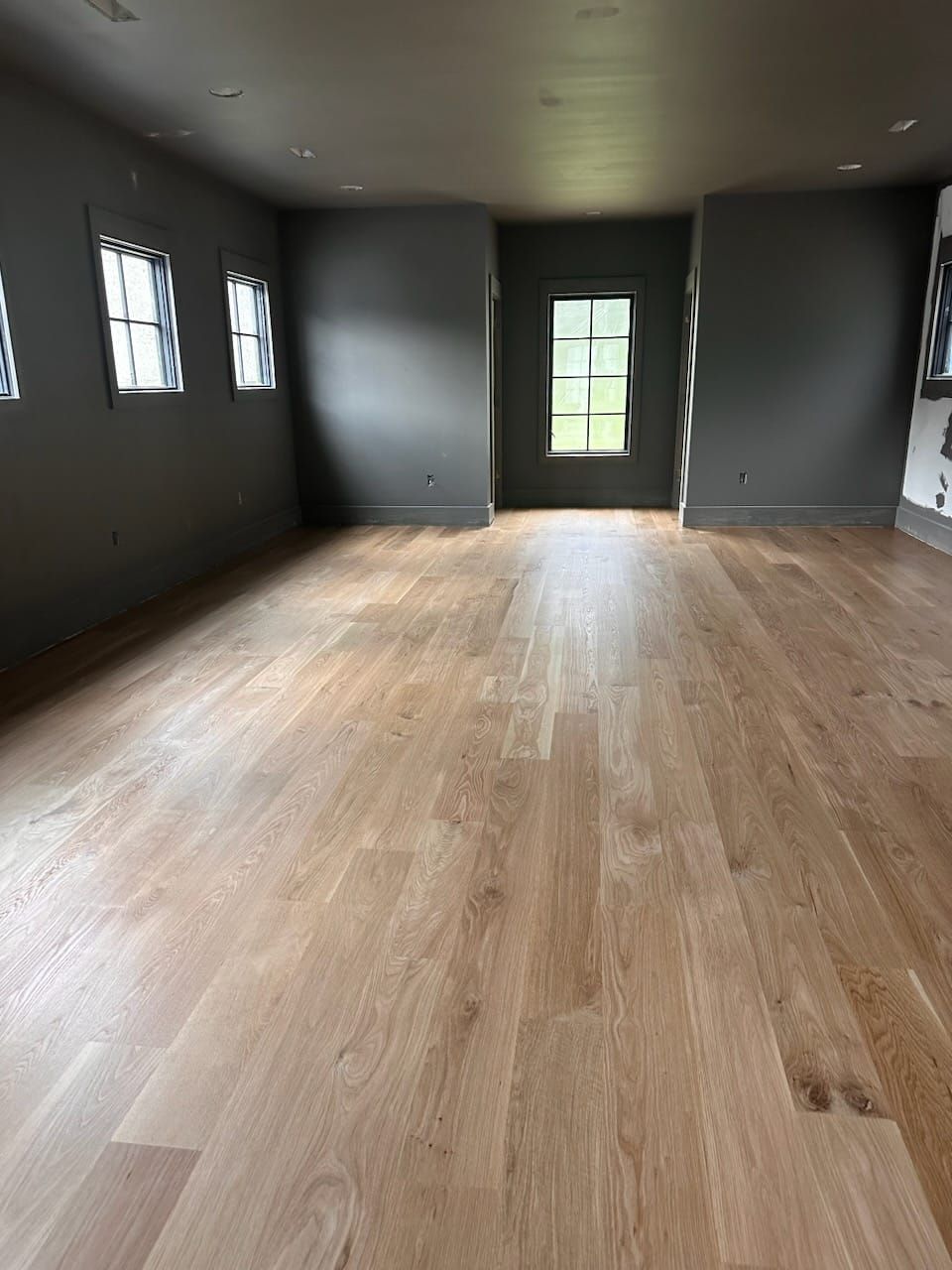 A large empty room with a wooden floor and gray walls.