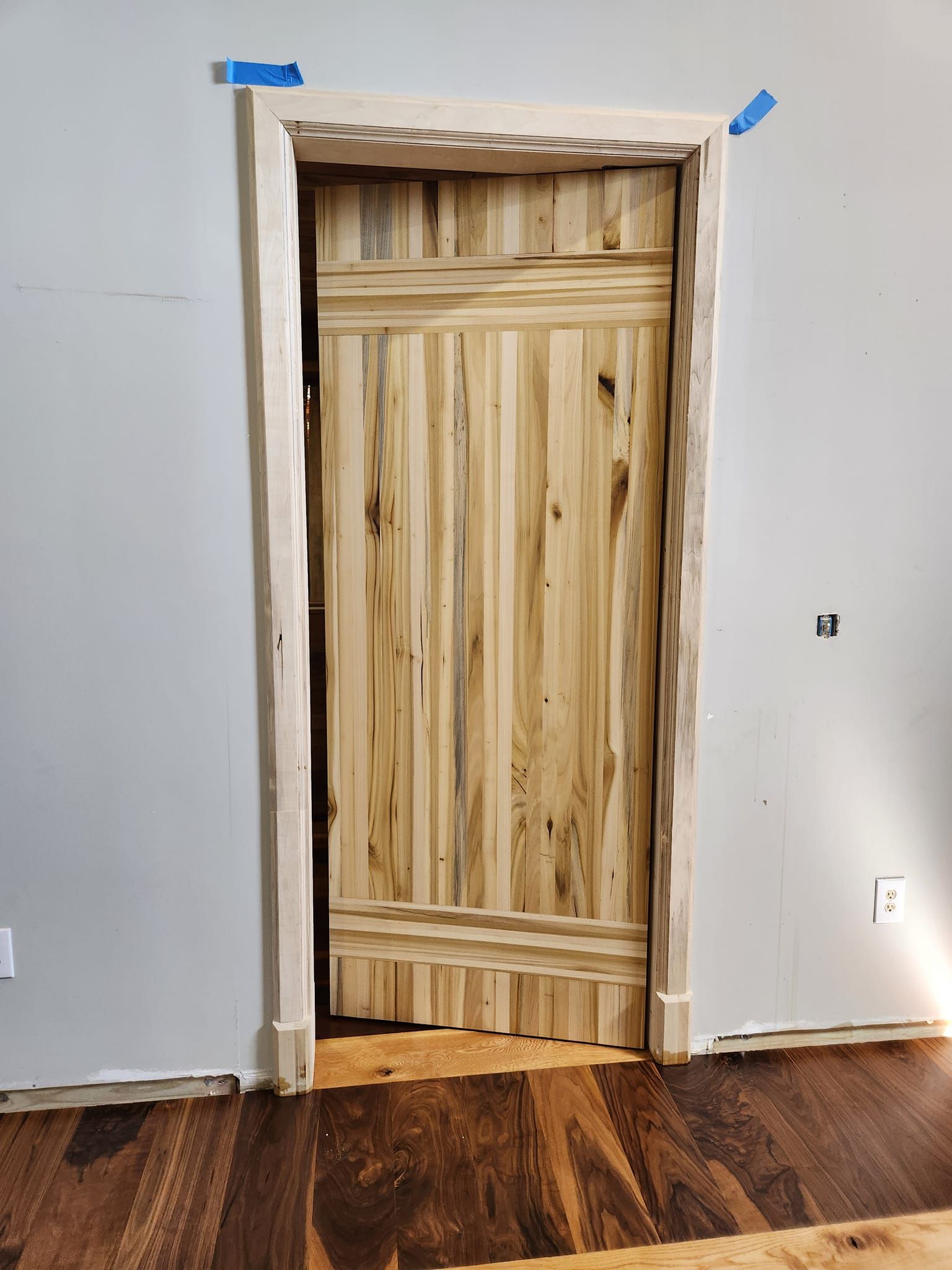 A wooden door is being built in a room with a wooden floor.