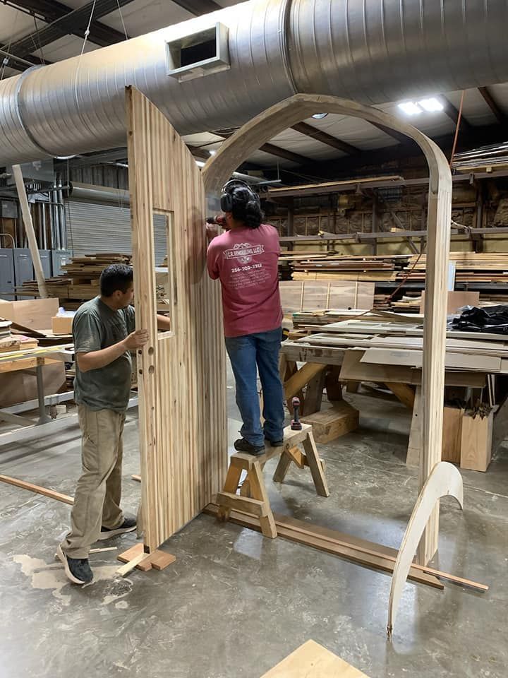 Two men are working on a wooden door in a factory.