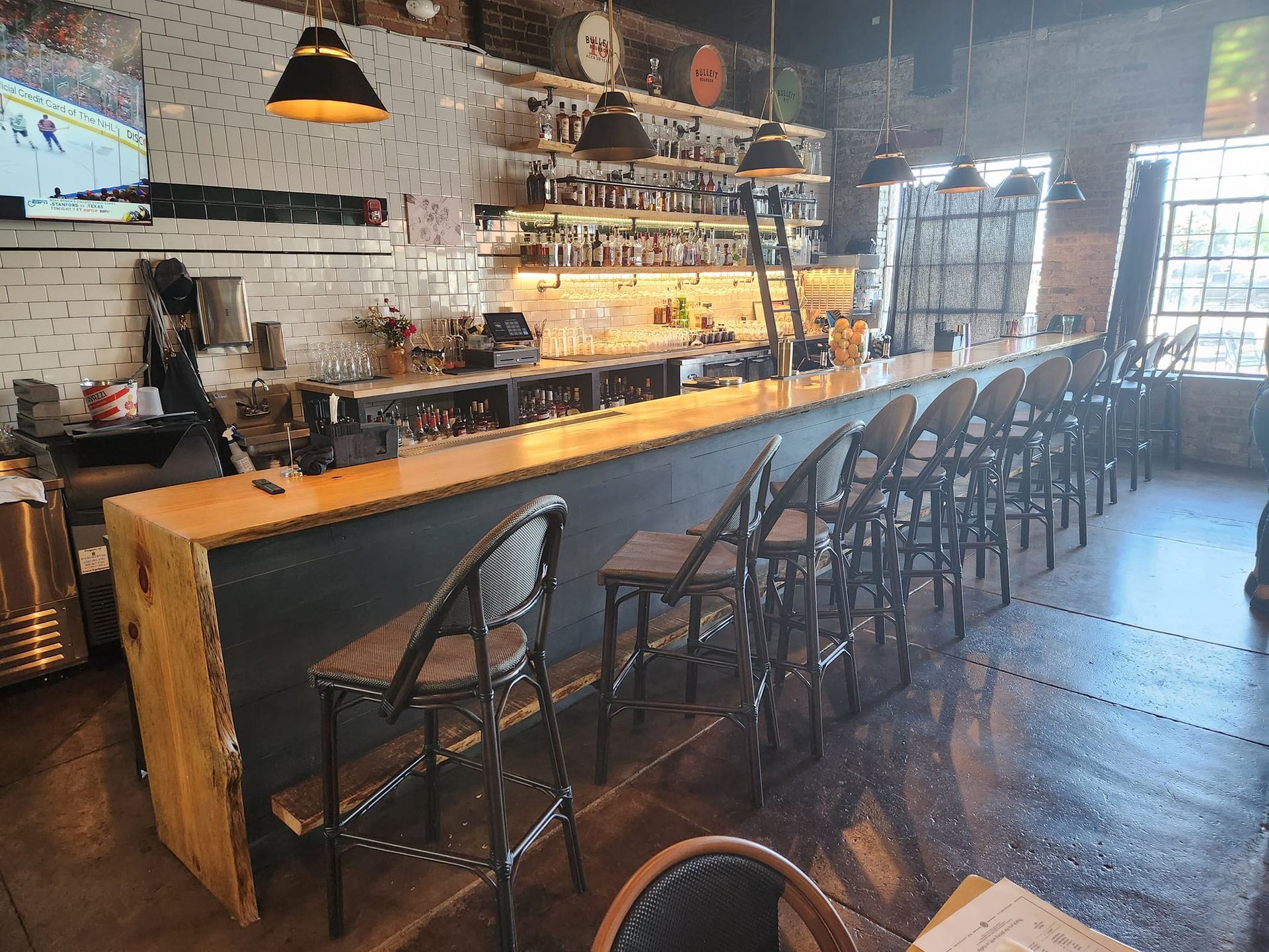 A restaurant with a long bar and a lot of chairs.
