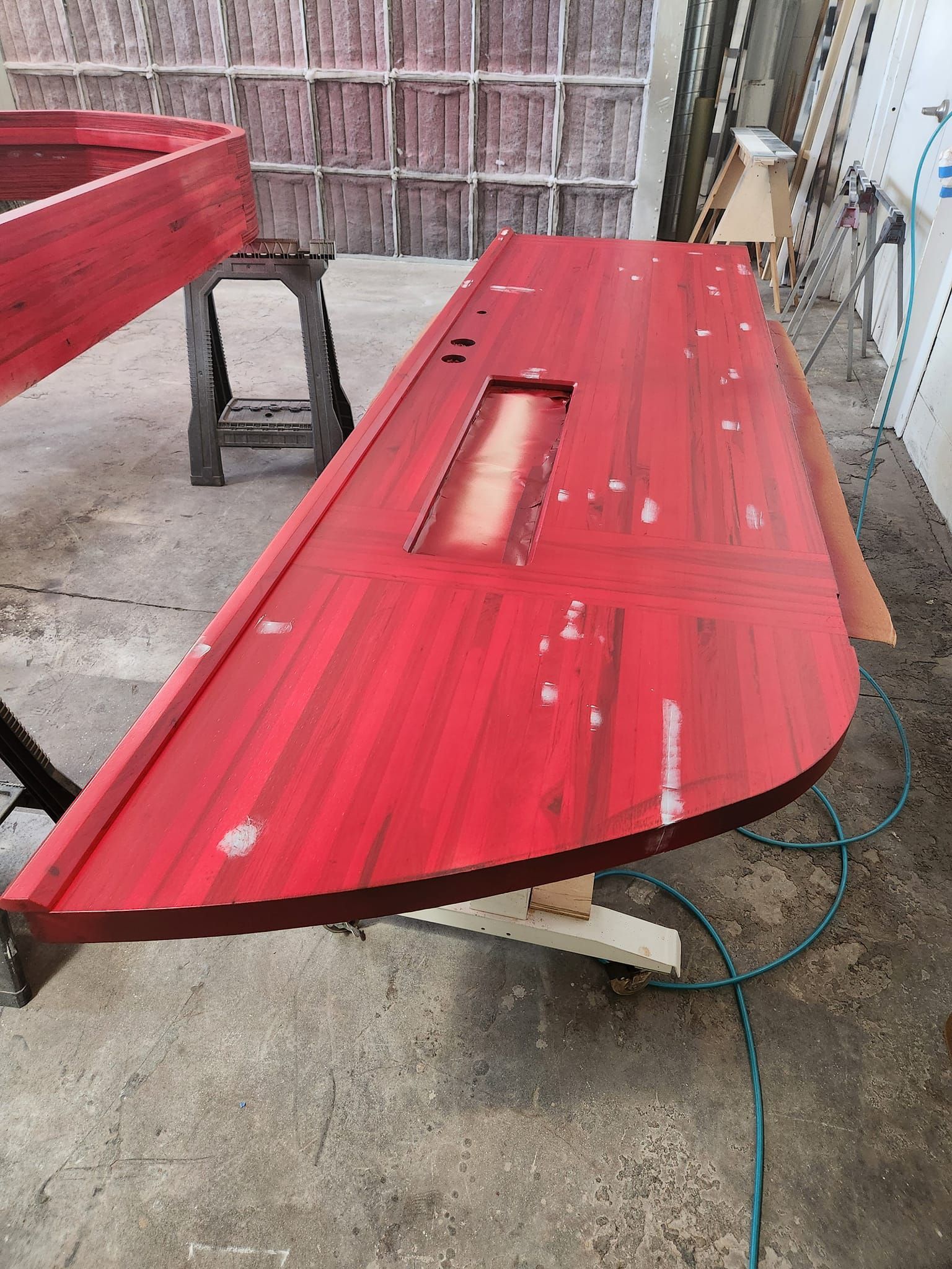 A red wooden table is sitting on top of a cement floor.