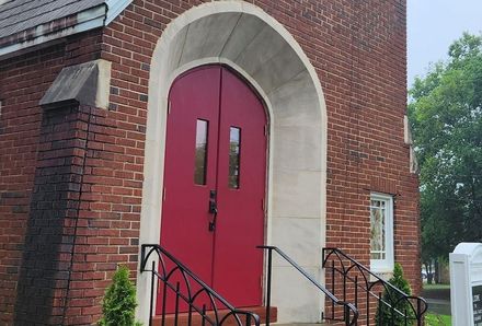 A brick building with a red door and stairs