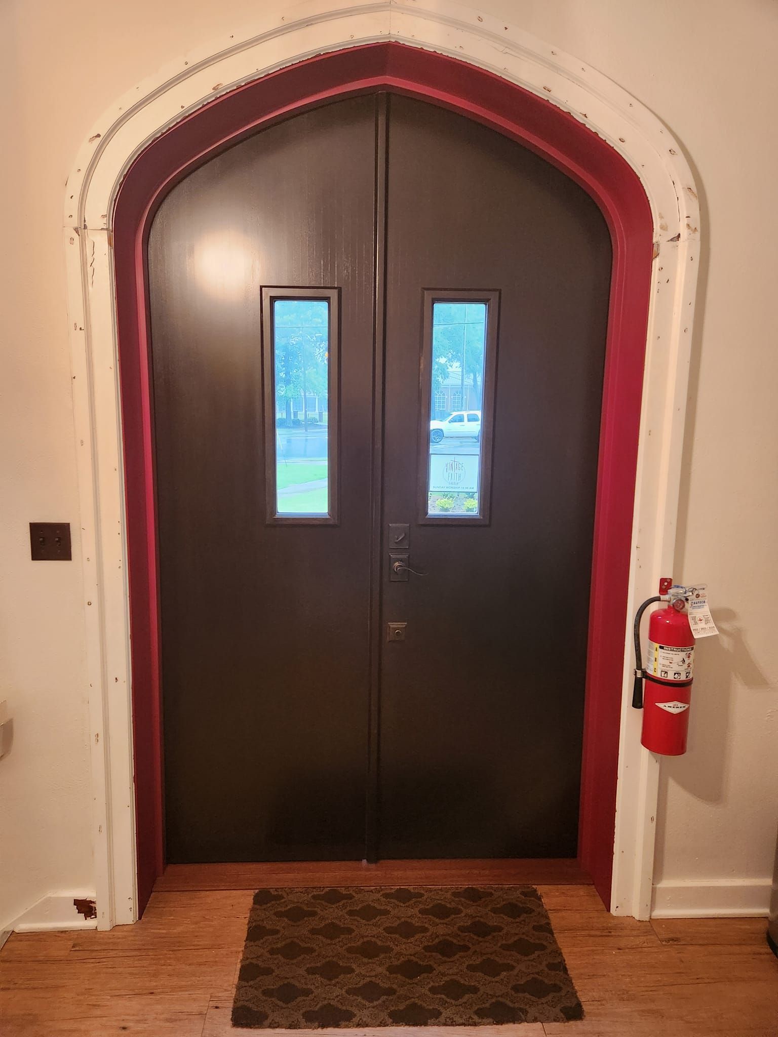 There is a fire extinguisher hanging on the wall next to the door.