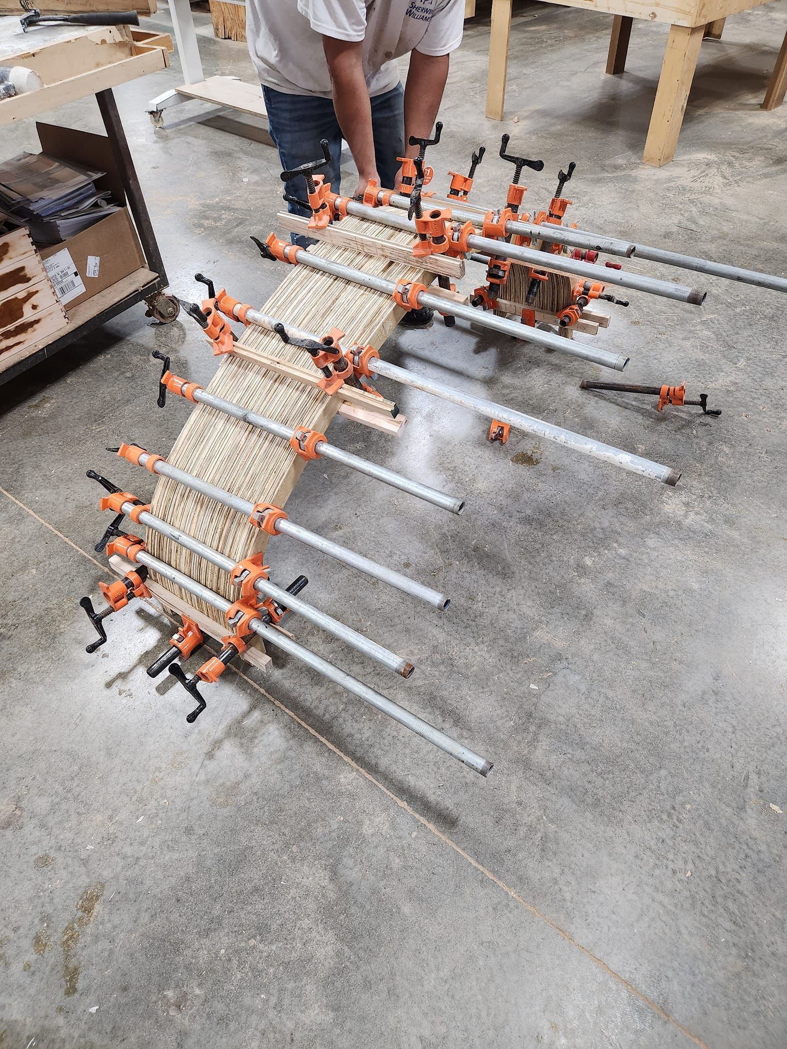 A man is working on a piece of wood with clamps.