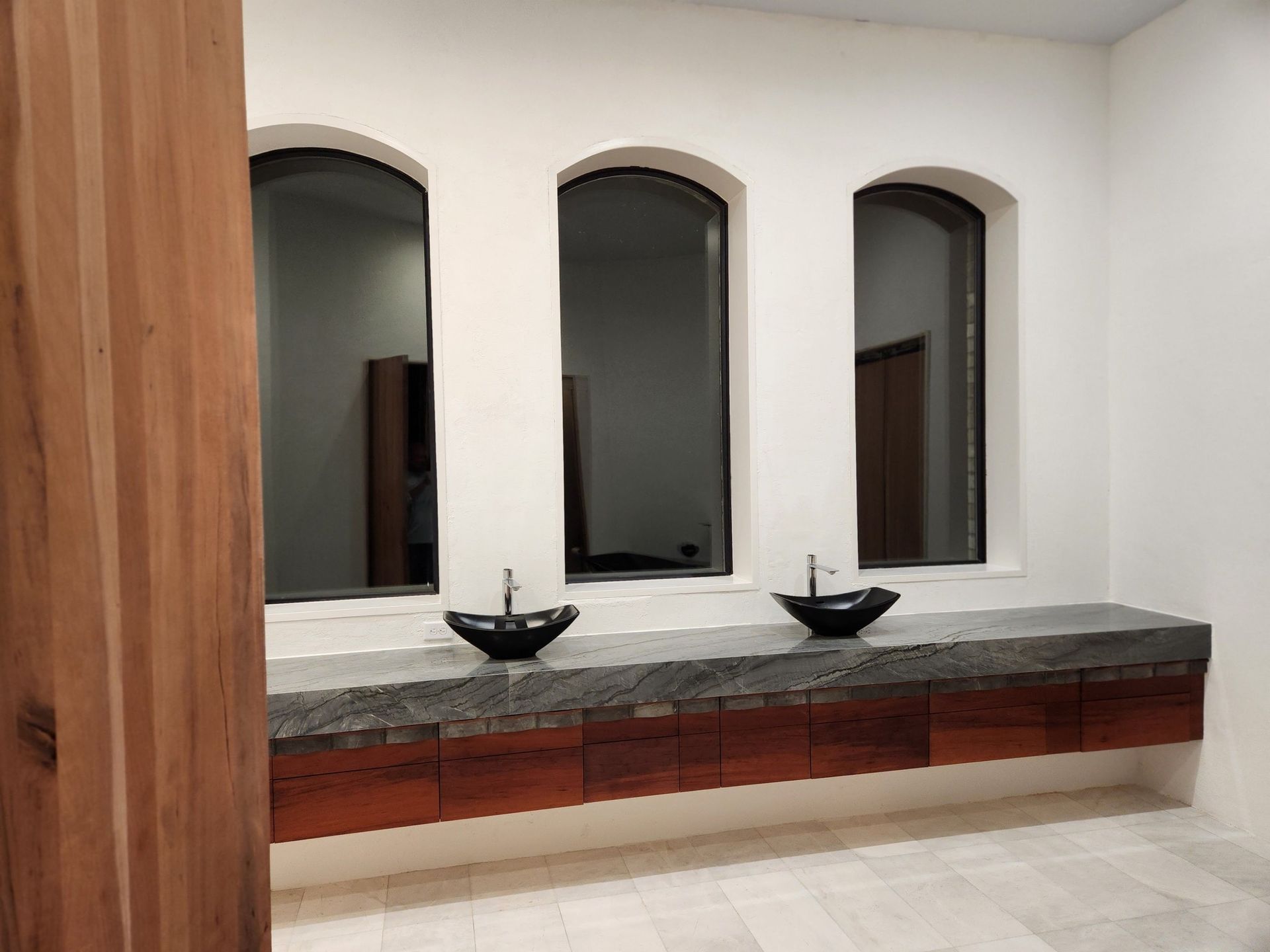 A bathroom with two sinks and three windows.