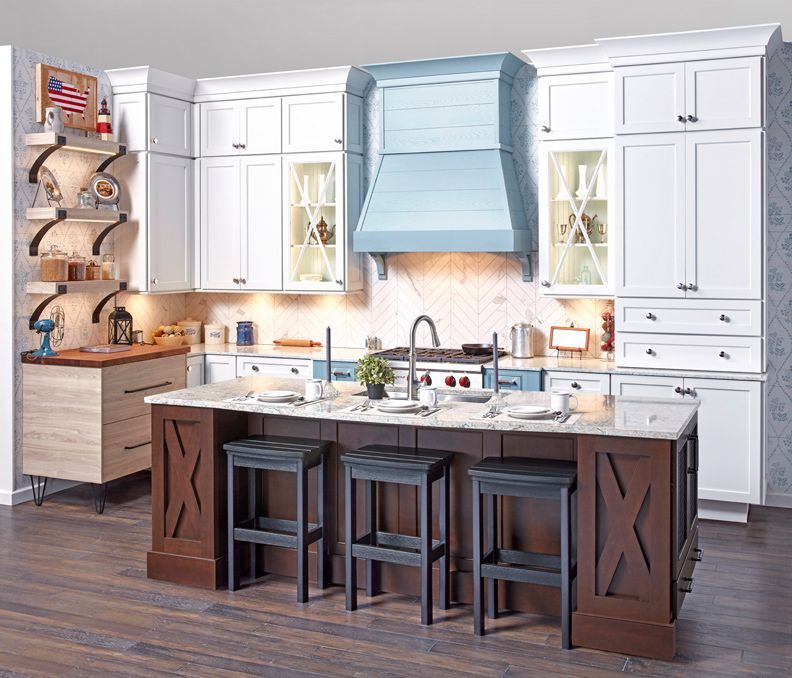 A kitchen with white cabinets , a large island , stools and a stove.