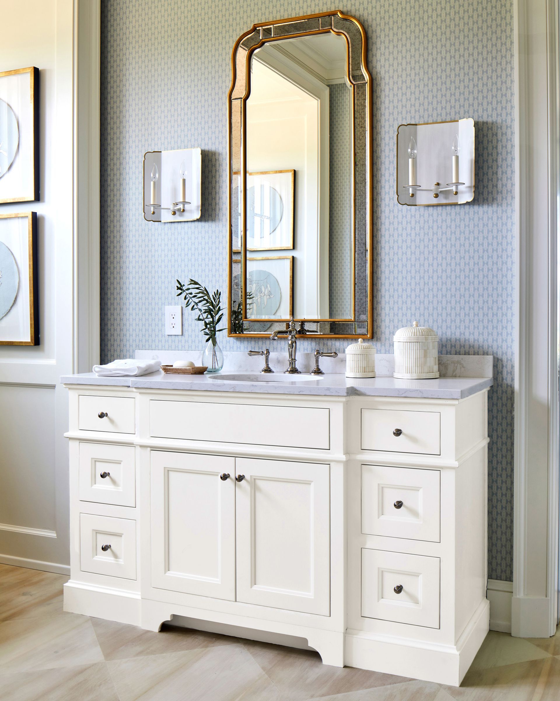 A bathroom with a white vanity and a large mirror.