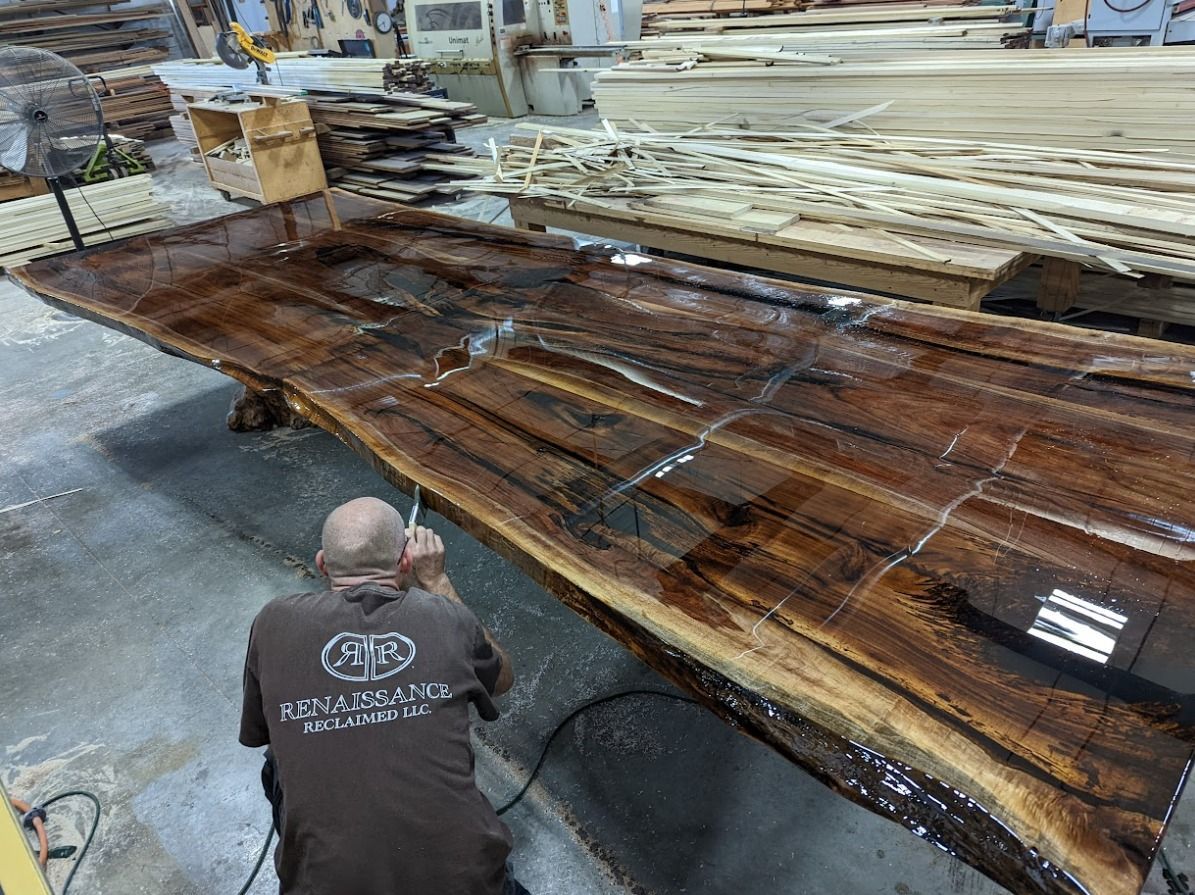 A man is working on a large piece of wood in a workshop.