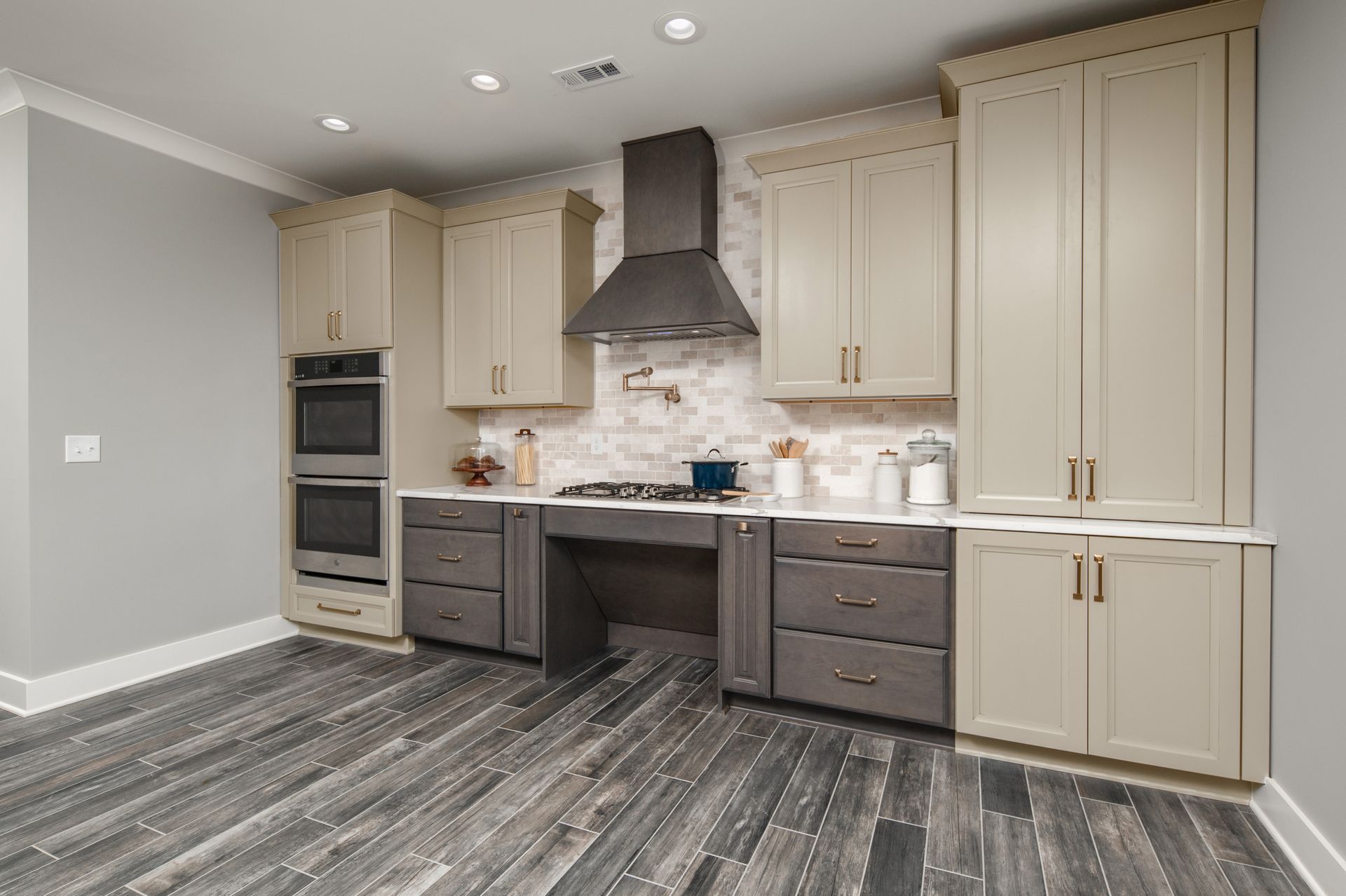 A kitchen with a stove , sink , cabinets and a wooden floor.