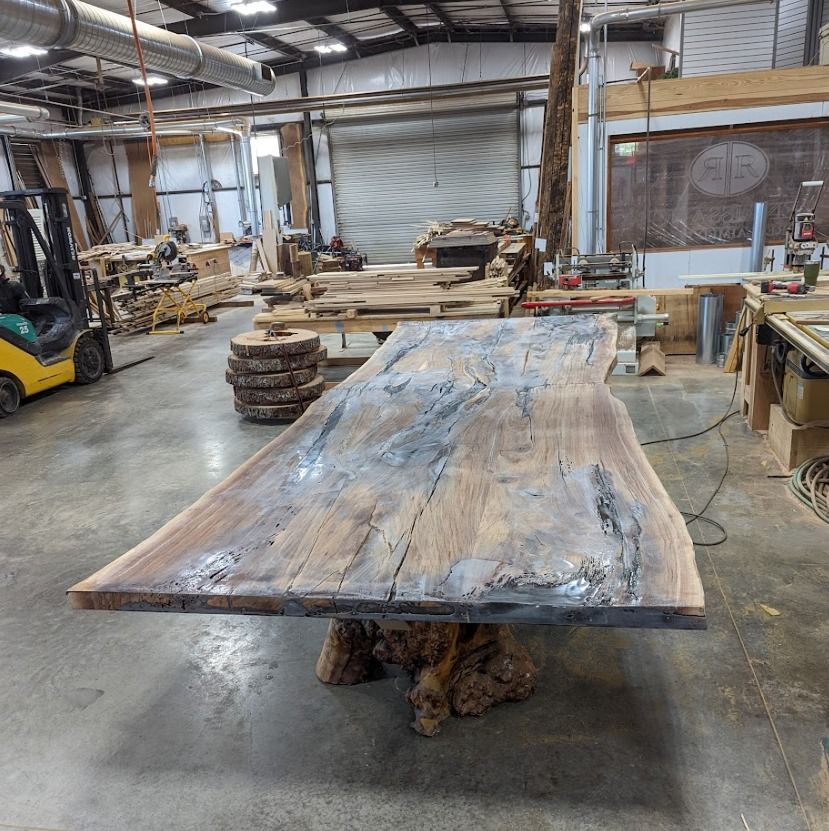 A large wooden table in a warehouse with a forklift in the background