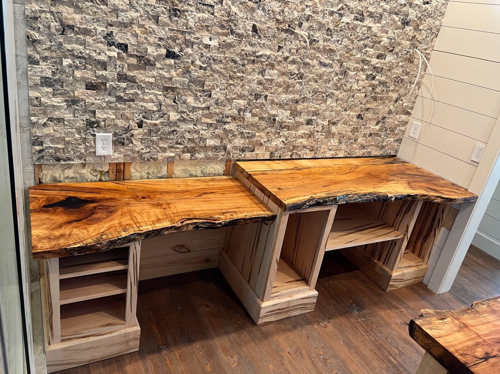 A wooden desk is sitting in front of a stone wall.