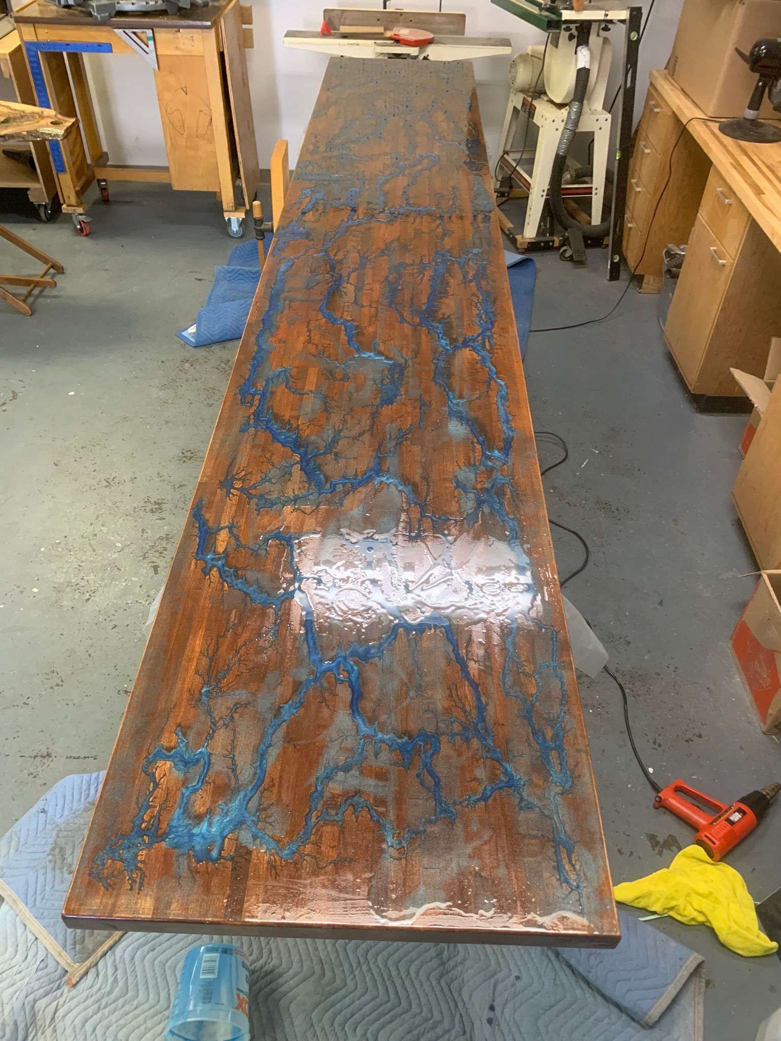 A long wooden table is sitting on the floor in a workshop.