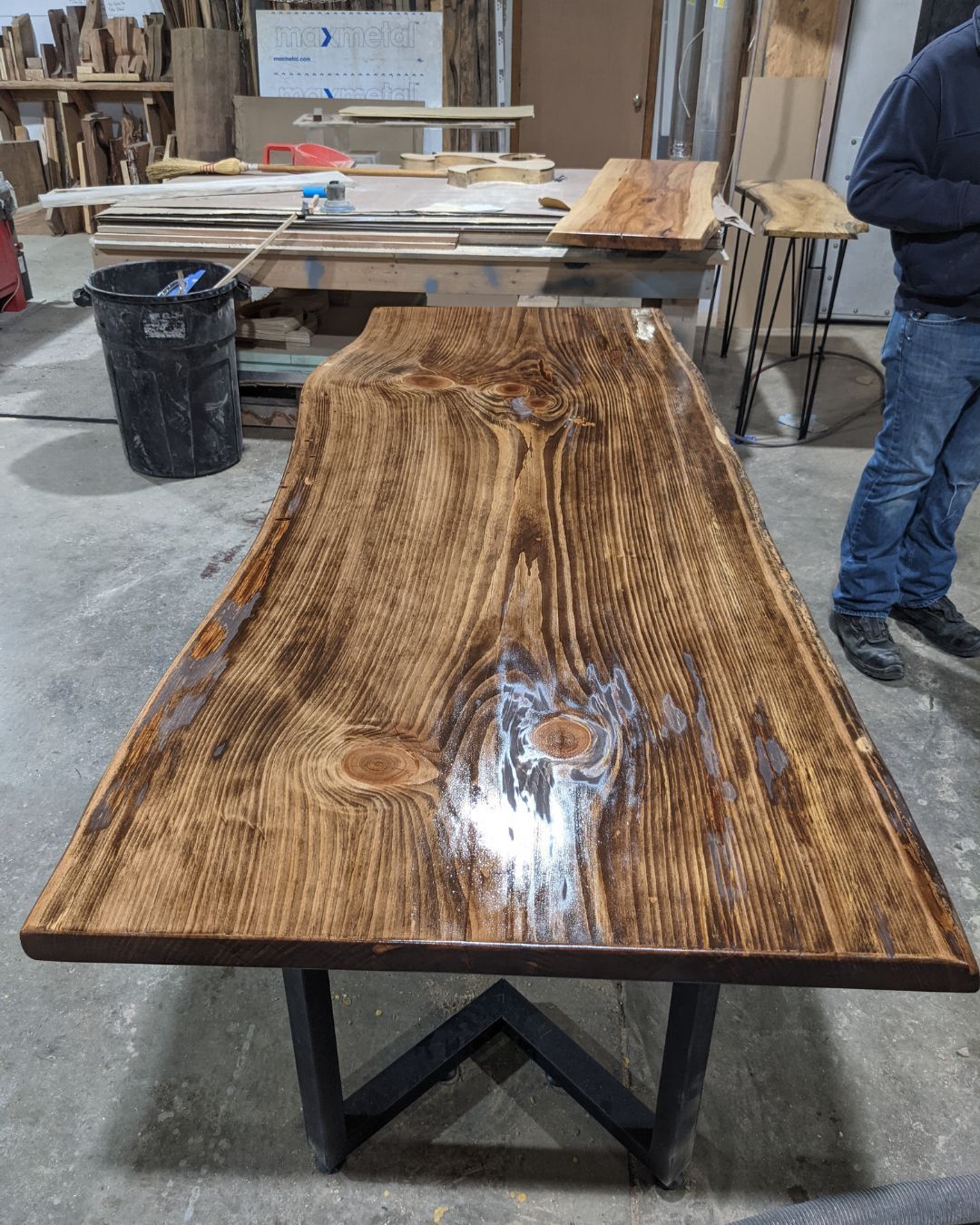 A man is standing next to a wooden table in a workshop.