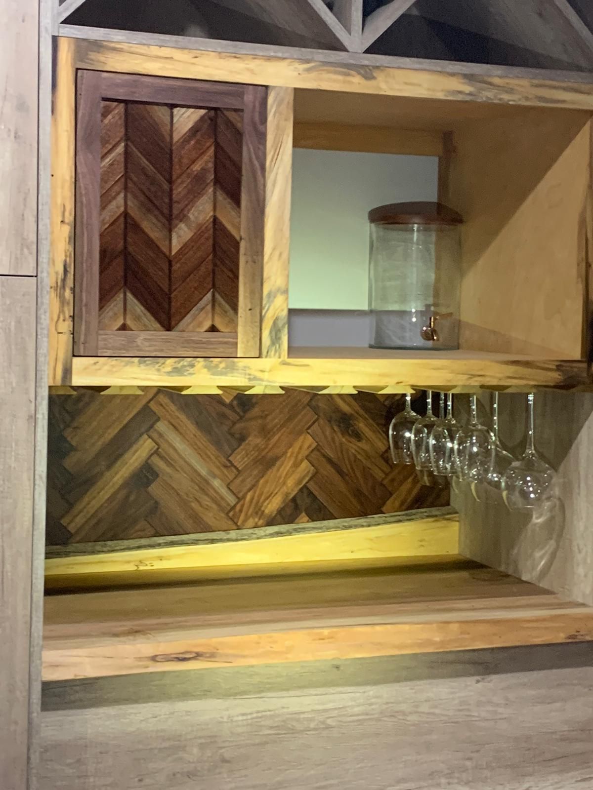 A wooden shelf with a water dispenser and wine glasses on it.